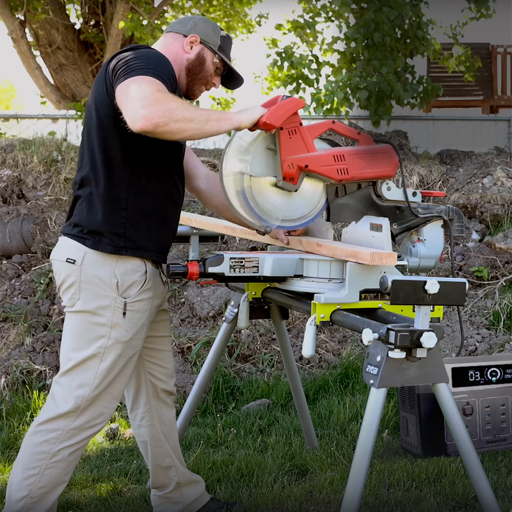 Man using miter saw outdoors powered by a portable station, showing off-grid work capability.