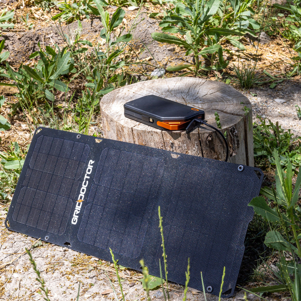 65W Power Bank connected to the solar panel next to a tree stump