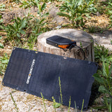 65W Power Bank connected to the solar panel next to a tree stump