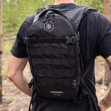 Hiker wearing Aquamira RIG 700 tactical hydration pack during outdoor trail and camping use