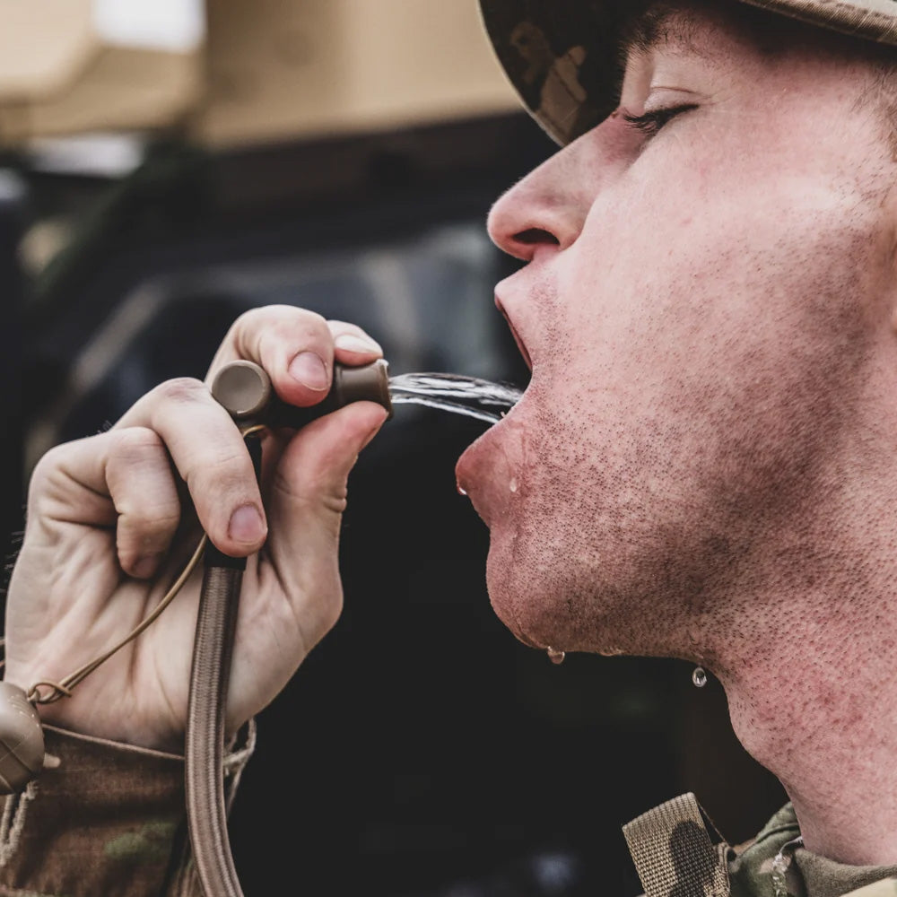 Outdoor user drinking from the Aquamira RIG 700 pressurized hydration pack drinking tube